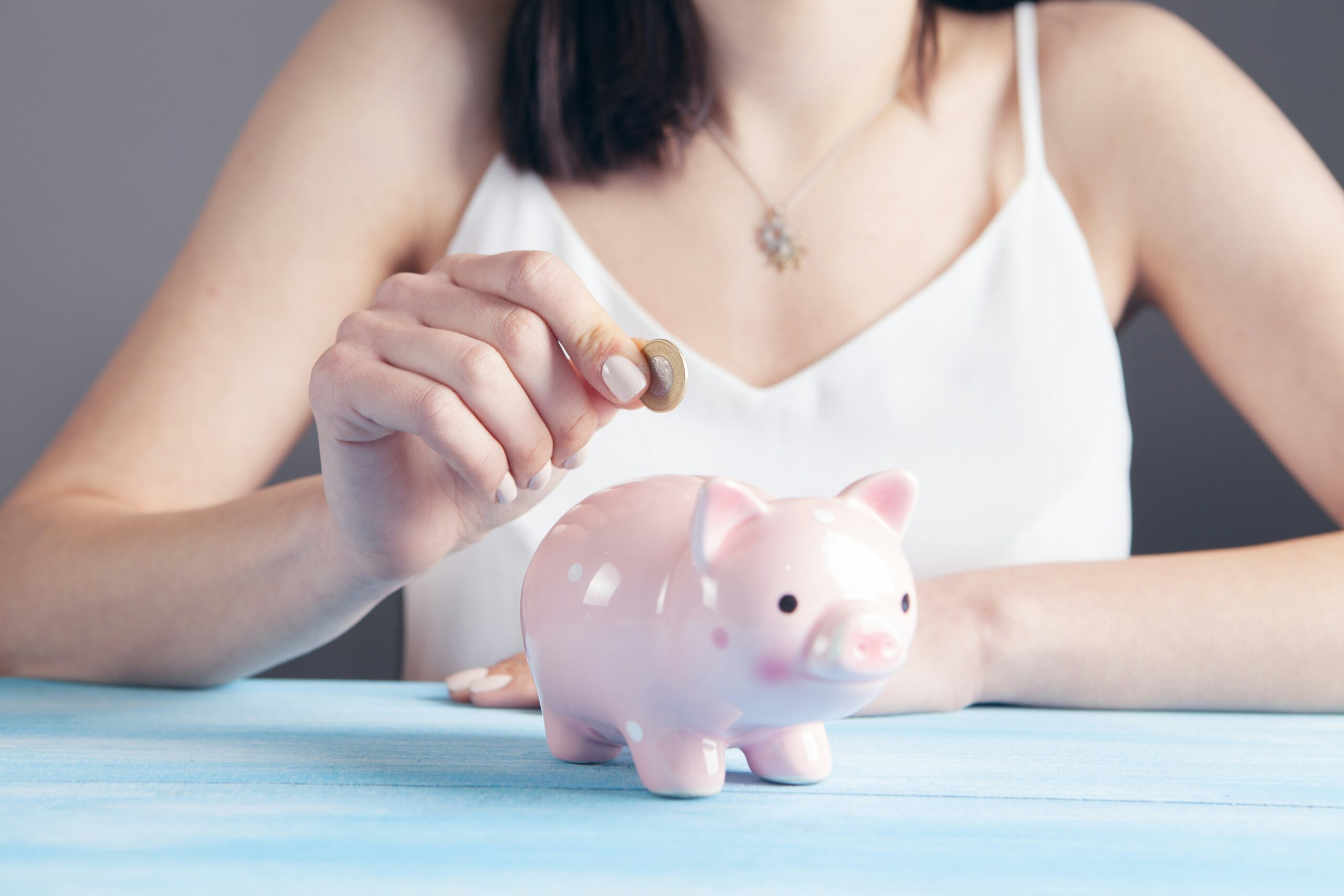 woman putting a coin into piggy bank