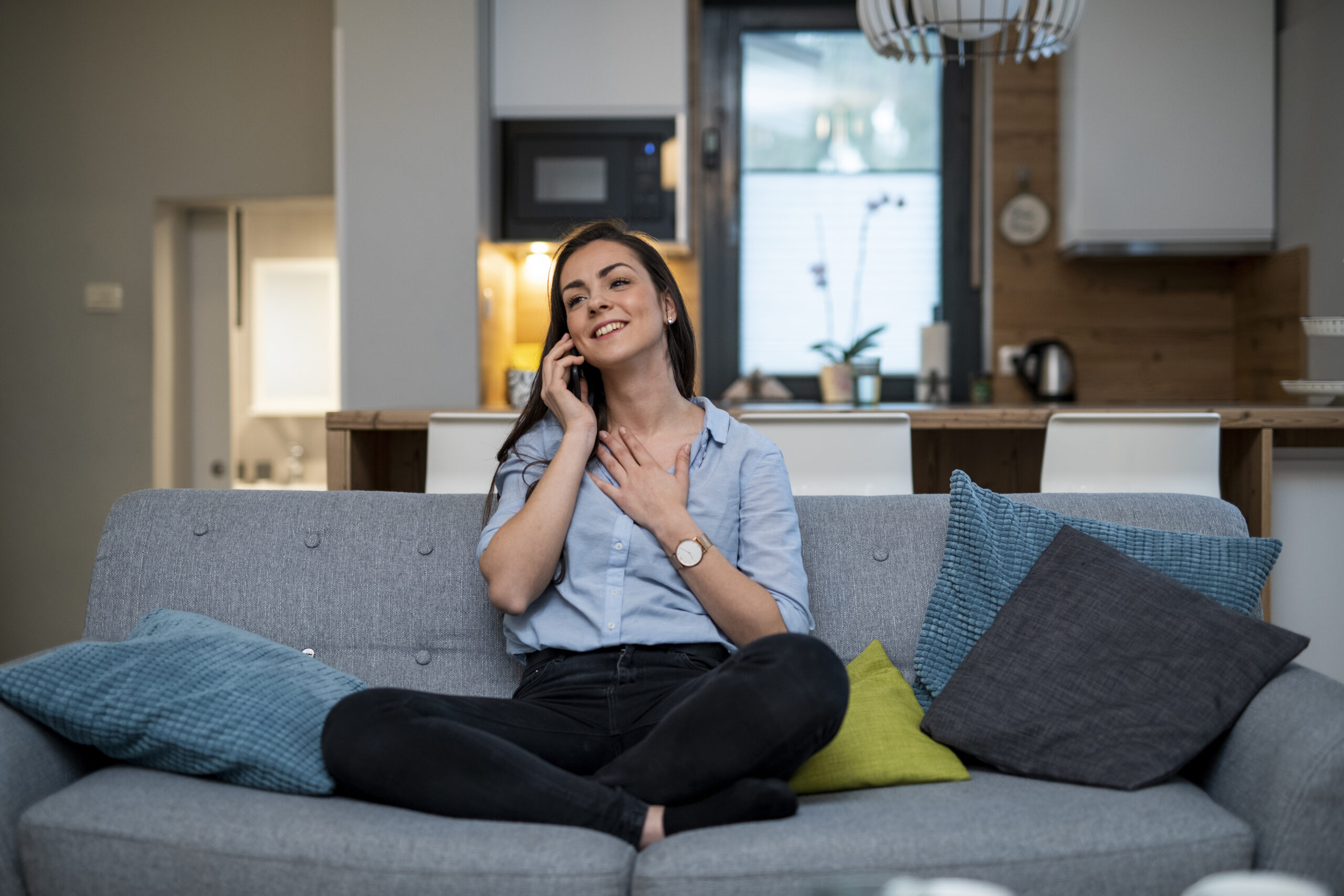 Young woman sitting on the couch and using smart phone