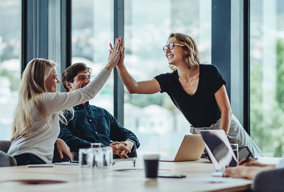 Female professional giving a high five to her colleague in conference room