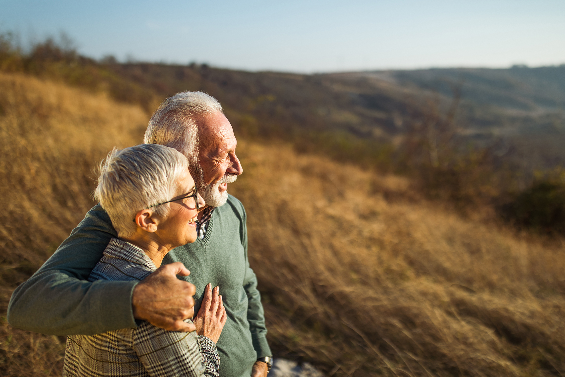 Happy mature couple enjoying while spending an autumn day on the hill