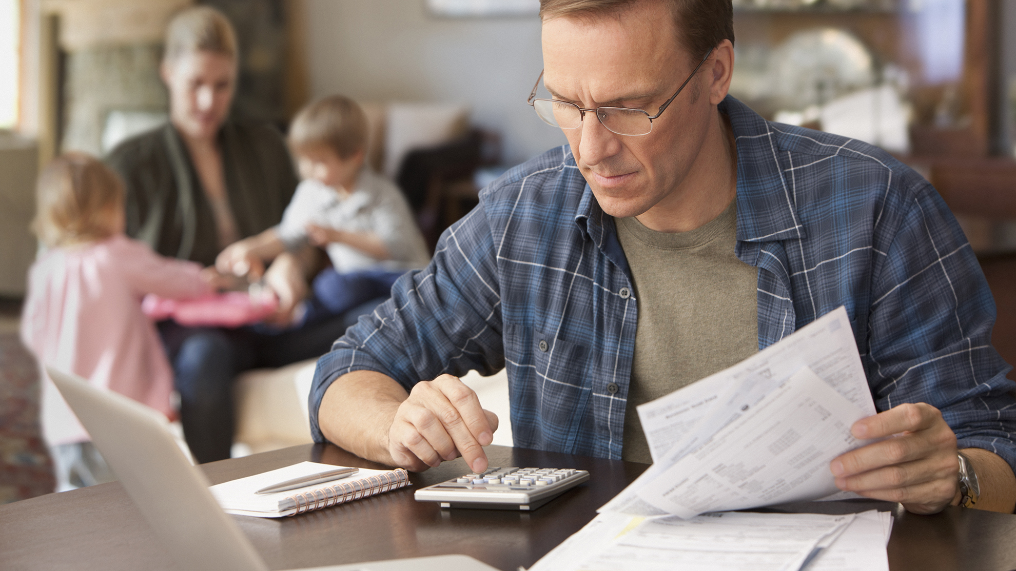 Father paying bills with family behind him
