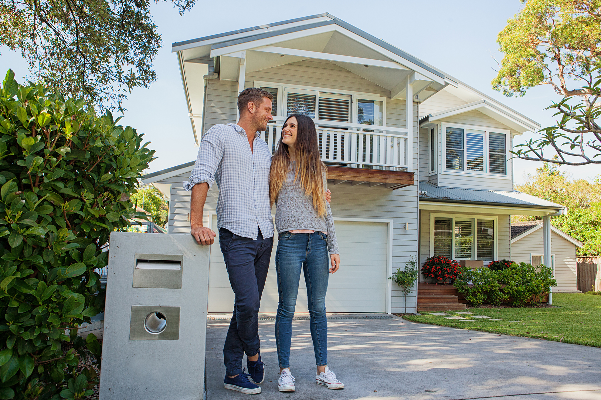 Happy couple standing in front of their home