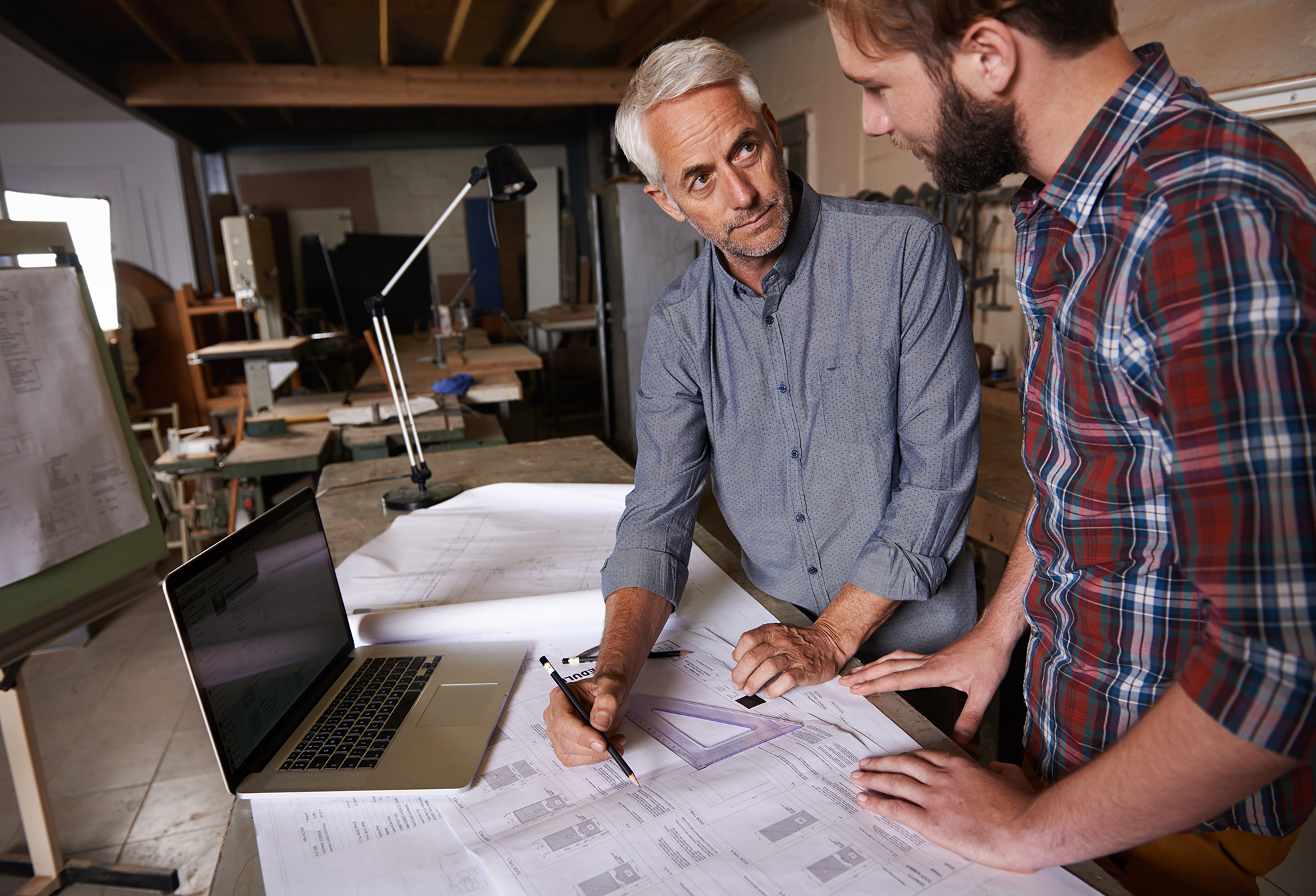 Two men standing in a workshop going over building plans