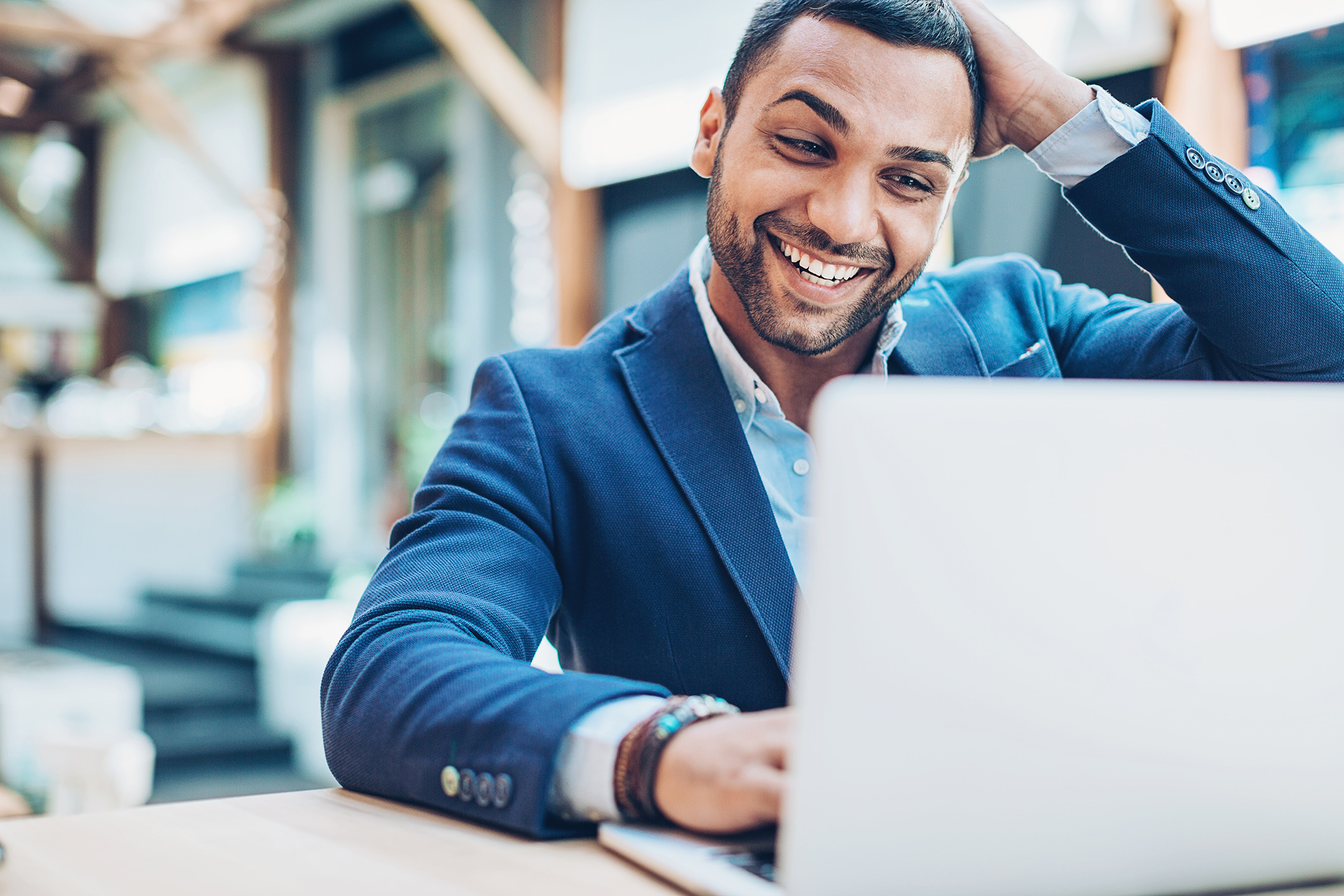 Young Middle Eastern ethnicity businessman looking at his laptop with happiness and excitement