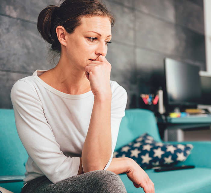 Sad woman sitting on a sofa in the living room